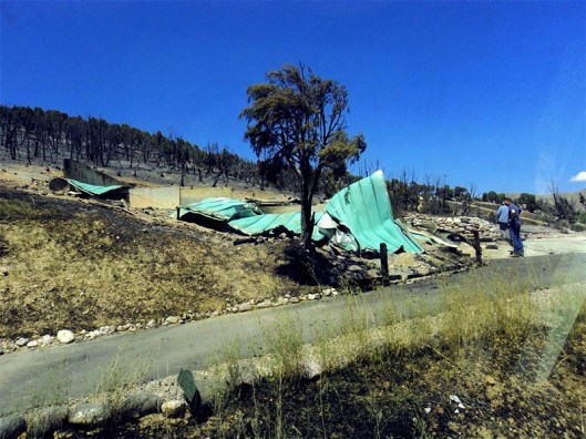 photo of burned house with metal roof twisted and collapsed.