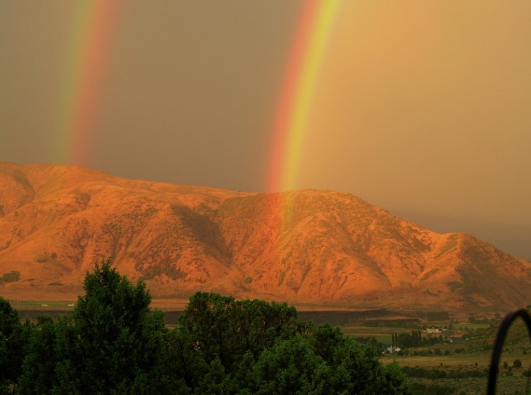 rainbow across mountain dust and smoke