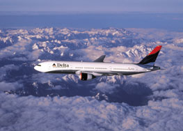 delta jet flying over snow covered mountains with blue sky and clouds