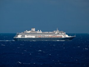 cruise ship with navy colored bottom half sailing on water that is navy colored with light chop