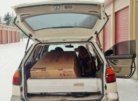 open hatch of a subaru with a bathtub box and a dog inside