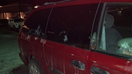 red van in dark parking lot with white handprints on it.
