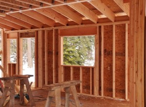 part way constructed kitchen. Saw horses and studs visible. Window and door show.