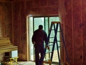 man with ladder putting insulation on walls of a house under construction
