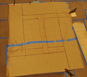 brown craft paper taped together with blue painters tape and hand drawen stone pattern and besse clips holding down the paper shown from above